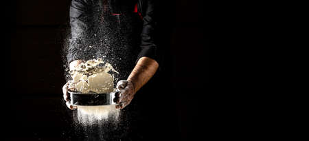 Powdery flour flying into air. chef hands with flour in a freeze motion of a cloud of flour midair....