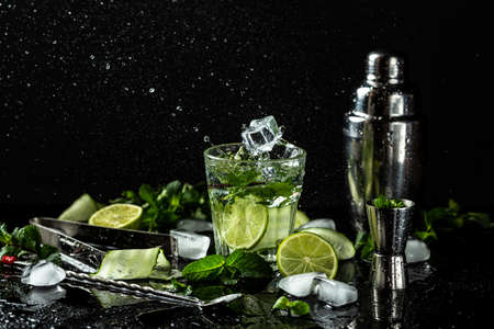 Fresh Mojito cocktail with lime, mint and ice in jar glass on dark background. drink in freeze motion, drops in liquid splash. The concept of summer citrus refreshing drinks, cocktails, lemonadeの写真素材