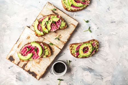 Vegan sandwiches with avocado, watermelon radish and microgreen. Delicious breakfast or snack on a light background, top viewの写真素材