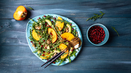 Persimmon, avocado salad with pumpkin seeds, walnuts, pomegranate and arugula. Diet menu. Vegan food. flat lay. Banner. top view.の写真素材