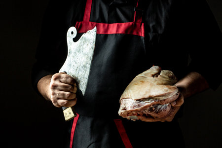 Cooking, butcher Man chef cuts with cleaver knife fresh pork knuckle. German cuisine, banner, menu, recipe, place for text.の写真素材