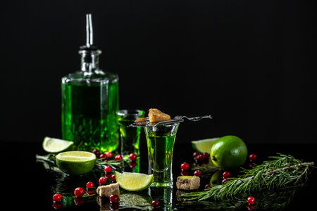 green cocktail on the basis of absinthe sugar cubes, brown sugar, cranberries and lime, stainless steel spoon. space for text.の写真素材