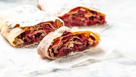 cherry homemade pie. cherry strudel of Austria, winter dessert strudel with cherry, cranberries and walnut on a light background, top viewの写真素材
