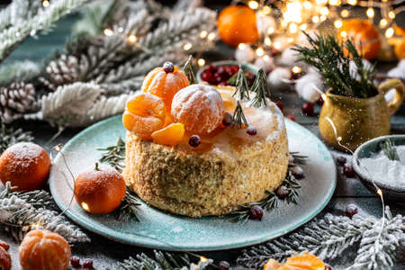 Christmas fruit cake, decorated with tangerines, rosemary in the form of Christmas trees. atmospheric photoの写真素材