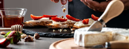 Bruschetta sandwiches with strawberries, cheese, camembert, brie, nuts and honey cooking by chef handの写真素材