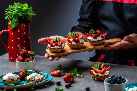 Close up master chef hands making a delicious strawberry tarts. Fruit dessert tarts with cheese creamの写真素材