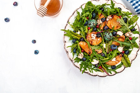 Arugula and peaches salad. Vegetarian gourmet salad made of caramelized grilled peaches slices, arugula leaves, goat cheese on a light background, top view.の写真素材