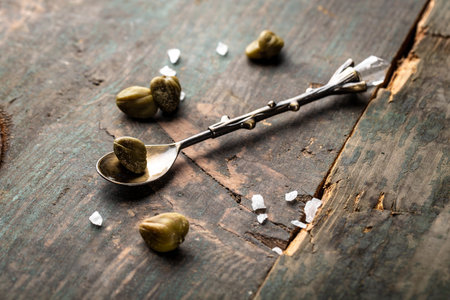 pickled capers on a dark wooden background. Edible flower buds of Capparis spinosa, caper bush or Flinders rose. Delicious ingredients for cooking.の写真素材
