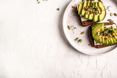 Bruschetta with avocado, cheese. The concept of eco products. Organic farm dairy products, cheeses, cereals. Parmesan, feta, goat cheese on light background. flat lay.の写真素材