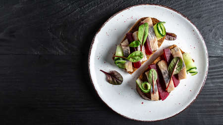Herring fillet. Sandwich with salted herring, slice beetroot, green cucumber, onion and microgreen...