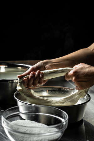 woman working in a small family creamery is processing the final steps of making a cheese, produces...