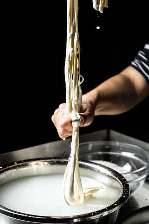 cheesemaker cuts the cheese freshly prepared. cheese silano or caciocavallo in cheesemaker hands. Traditional Italian mozzarella.の写真素材