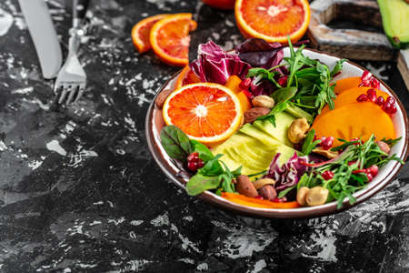 Vegetarian salad. Clean healthy food concept. Buddha bowl with avocado, blood orange, broccoli, watermelon radish, spinach, quinoa, pumpkin seeds. space for text. top view.の写真素材