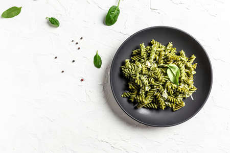 Green spinach pasta with cheese in a black bowl on light background. banner, menu recipe place for text, top view.の写真素材
