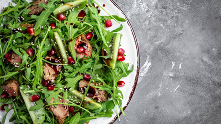 Diet menu. Healthy salad of fresh arugula, chicken liver, kiwi and pomegranate on a bowl. Flat lay....