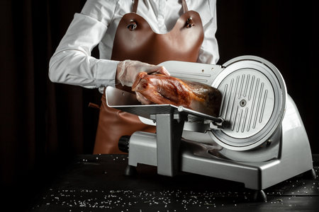 Dry Spanish ham on cutting machine, Iberian ham cutter on black background.の写真素材