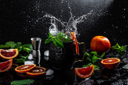 Moscow mule cocktail splashing in copper cup with lime, blood orange, ginger beer, vodka and mint, freeze motion.の写真素材