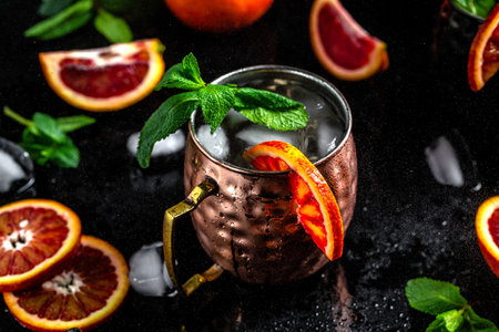 Famous Moscow mule alcoholic cocktail in copper mug with blood orange, ginger beer, vodka and mint close-up.の写真素材