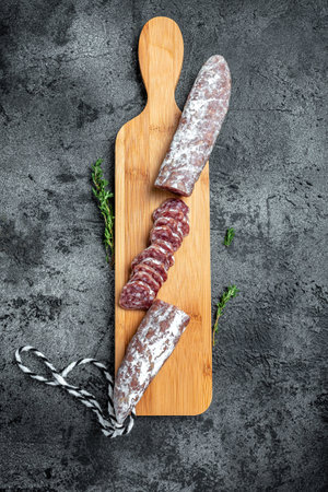 Fuet Salami cut in slices. Traditional Spanish sausage on wooden board. Fuets Catalan dry sausages. vertical image, place for text Top view.の写真素材
