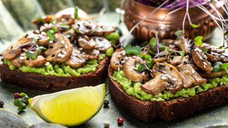 Toast avocado, mushrooms and microgreen whole grain sandwich. Decorated with sesame. Vegetarian food. Vegan menu. Food recipe background. close up.の写真素材
