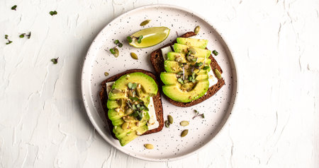 Healthy avocado toasts for breakfast or lunch with rye bread, sliced avocado, cheese, pumpkin and sesame seeds. banner, catering menu recipe top view.の写真素材