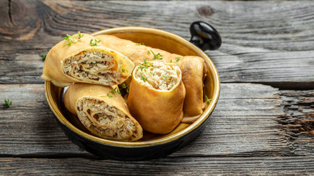 Crepes or pancakes stuffed with chicken meat on the wooden table. Long banner format, top view.