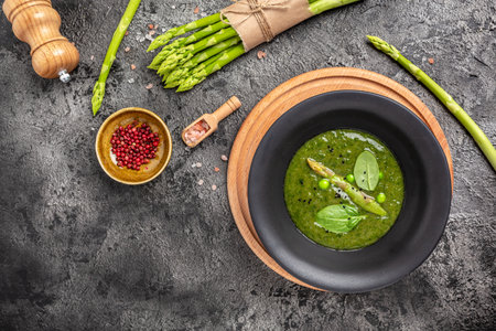 Delicious soup with asparagus in ceramic bowl, on rustic wooden background. Clean eating, dieting, vegan, vegetarian, healthy food concept. top view.の写真素材