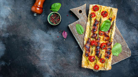 Asparagus quiche. Homemade tart with asparagus wrapped with bacon, spinach, cherry tomatoes and cheese. Ketogenic paleo diet. place for text, top view.の写真素材