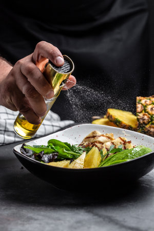 Healthy vegetable buddha bowl lunch with grilled chicken breast, halloumi, pineapple, avocado, green rocket salad, lime. addition of olive oil freezing in the air.の写真素材