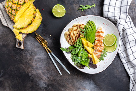 healthy and balanced food. grilled chicken breast, halloumi, pineapple, avocado, green rocket salad, lime. banner, menu recipe place for text, top view.の写真素材