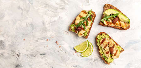 Bruschetta, toasted grilled Halloumi cheese and slices of avocado guacamole on white background top view with space for text. Health food. long banner format,の写真素材