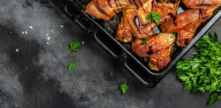 Baked chicken wings and legs of barbecue on dark stone table. Long banner format, top view.の写真素材