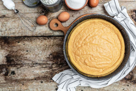 Homemade sponge cake with ingredients on a white wooden table. Bakery background concept. banner,...