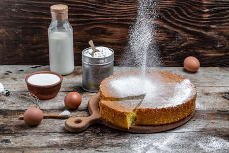Homemade classic sponge cake or biscuit sprinkled with powdered sugar in a freeze motion of a cloud of powder midair. Bakery background concept. banner, menu recipe place for text,の写真素材