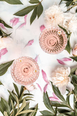 Rose wine in glass and peony flowers over white background, Summer celebration, wedding greeting card, invitation concept. vertical image. top view.の写真素材