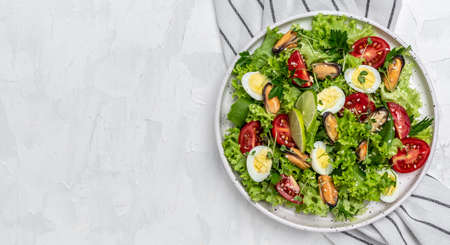Healthy vegetable salad with mussels, mussels, quail, egg, conjugate, lime, spinach, lettuce cherry tomatoes and microgreen. Diet menu top view.の写真素材
