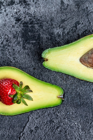 Avocado cut half and slice with strawberry. Detox concept. vertical image. top view.の写真素材