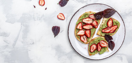 breakfast toast with guacamole, strawberries and chia seeds. Healthy snack. Avocado with strawberries. Keto diet toast. Vegan healthy food concept. Long banner format. top viewの写真素材