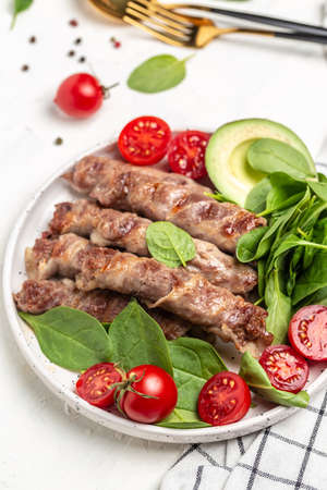 Ketogenic diet, grilled sausages minced meat wrapped in bacon with spinach, avocado and cherry tomato. chevapchichi or Kofta kebab, Keto paleo diet menu,の写真素材