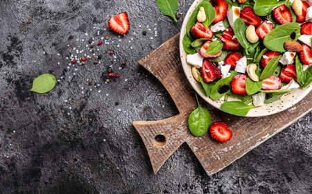 bowl of salad with strawberry, spinach leaves, nuts and feta cheese, balsamic vinegar. Detox and healthy superfoods bowl concept.の写真素材