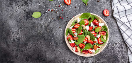 Diet menu. Healthy salad of fresh strawberry, spinach leaves, nuts and feta cheese, balsamic vinegar. Vegan food. Long banner format. top view.の写真素材