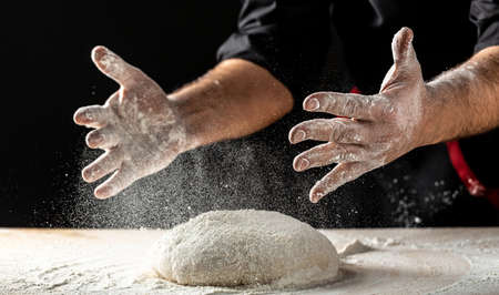 Clap hands of baker with flour. Beautiful and strong men's hands knead the dough make bread, pasta...