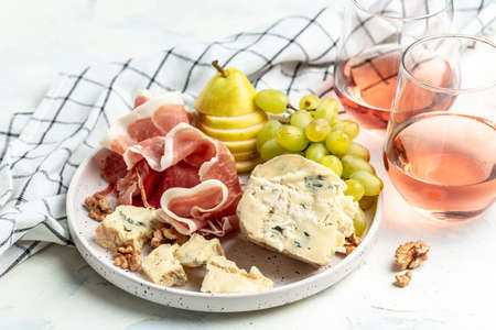 Glasses of rose wine with piece of blue cheese with vibrant grapes, walnuts and pear, party celebration concept. Food recipe background. close up.の写真素材