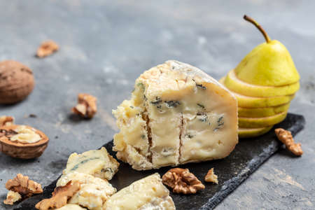 piece of blue mold cheese danablu, gorgonzola, roquefort with pear and walnuts. top view.