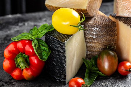 Set of hard cheeses with tomatoes and basil. traditional pieces of Spanish, French, Italy cheese.