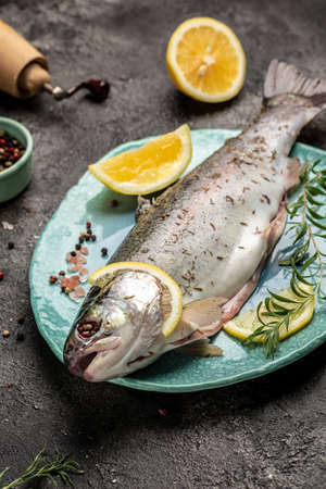 Fresh rainbow trout with salt, pepper, lemon and rosemay. Tasty fishes preparing for lunch. healthy eating concept. vertical image. top view. place for text.の写真素材