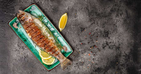 Plate with baked rainbow trout, lemon. Tasty fishes preparing for lunch. Healthy eating concept....