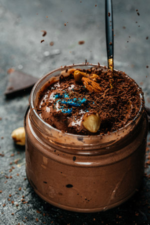 Jar of chocolate ice cream with nuts on dark background, vertical image. top view. place for text.の写真素材