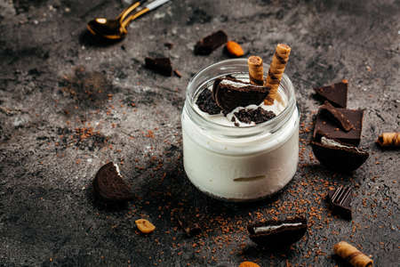 Chocolate cookie and ice cream in a glass jar. sweet dessert on dark background. banner, menu,...