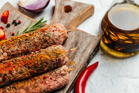 Fresh raw beef meat kebabs sausages with spices on a cutting board light background. Turkish...